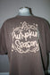 A brown short-sleeve t-shirt displayed on a mannequin torso, featuring a large cream-colored graphic on the front that reads 'Pumpkin Season' inside a pumpkin outline.