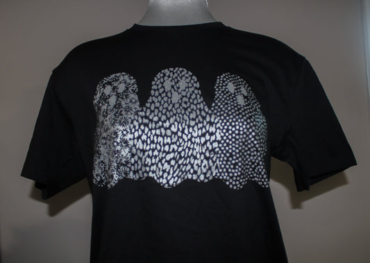 A black short-sleeve t-shirt displayed on a mannequin torso, featuring a large graphic print of three wavy ghost shapes filled with a white and gray spotted pattern resembling animal print or scales.